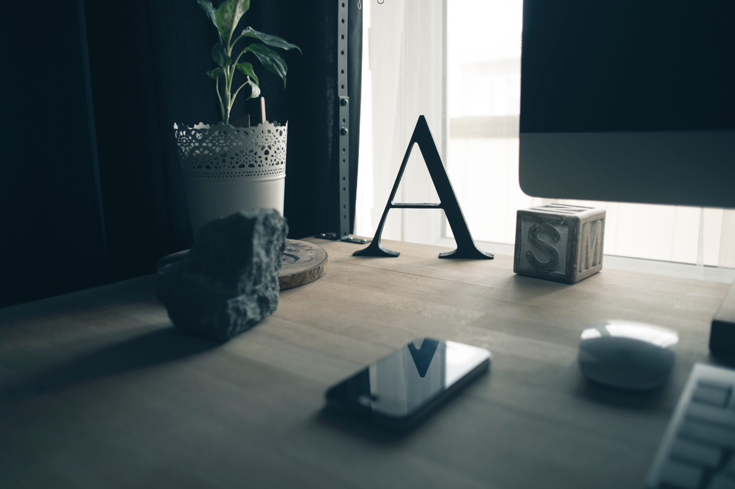 Schreibtisch mit Monitor, Zimmerpflanze und Dekorationsbuchstaben