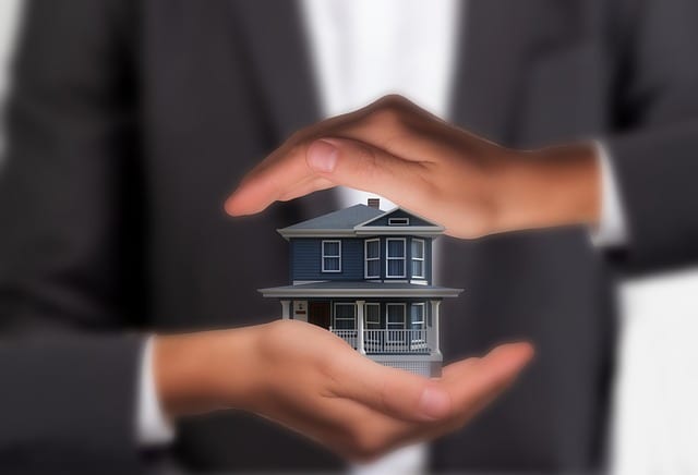 Zwei Hände schützen ein Modellhaus